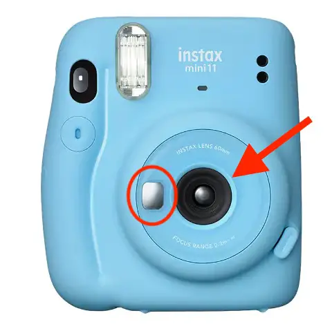 The selfie mirror and camera lens on the front of an Instax Mini 11. 