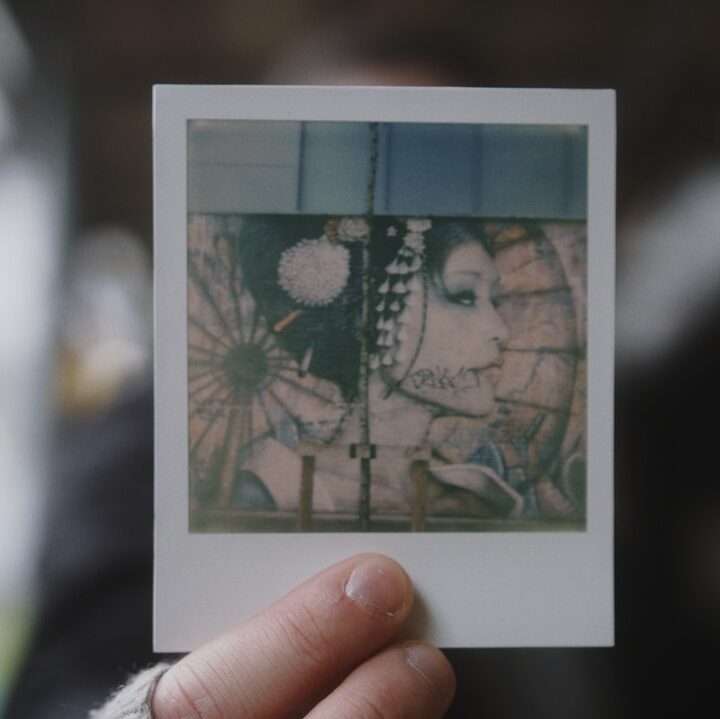A picture of a Polaroid with a smart phone while holding it in your hand